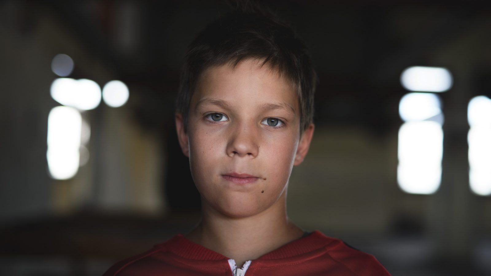 Dreng i rød hættetrøje kigger ind i kameraet