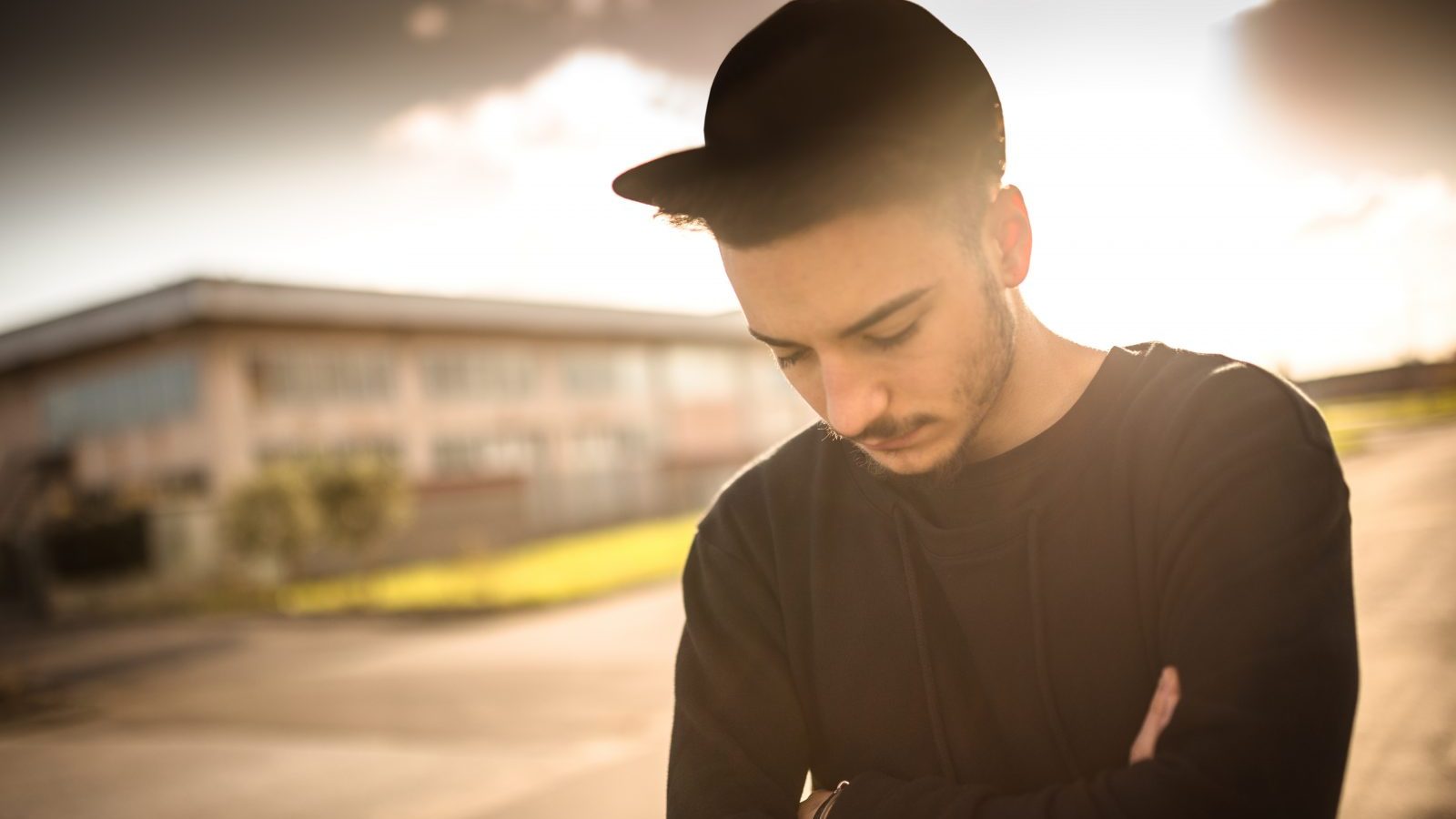 Mørkhåret ung mand med kasket kigger ned i jorden