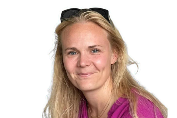 Blond kvinde med solbriller på hovedet smiler til kameraet