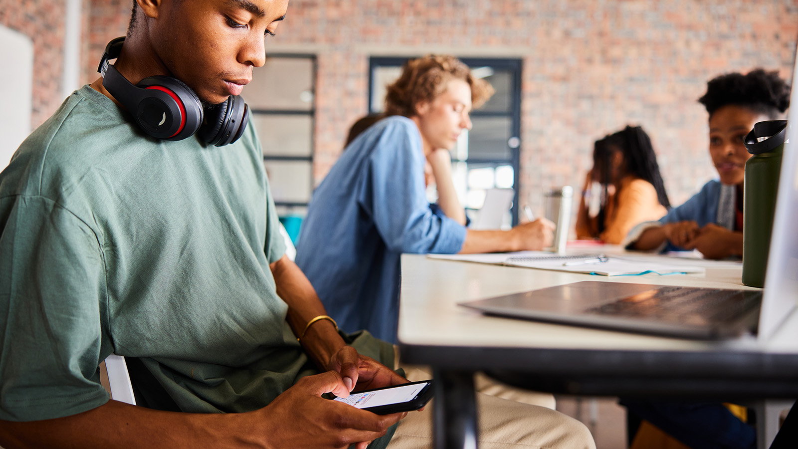 Dreng sidder ved bord og kigger ned på sin mobil