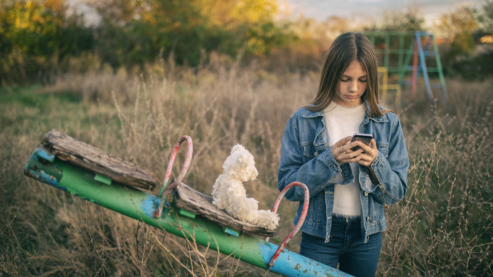 Pige i blå jakke kigger på sin telefon