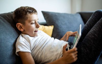 Dreng sidder på sofa med iPad