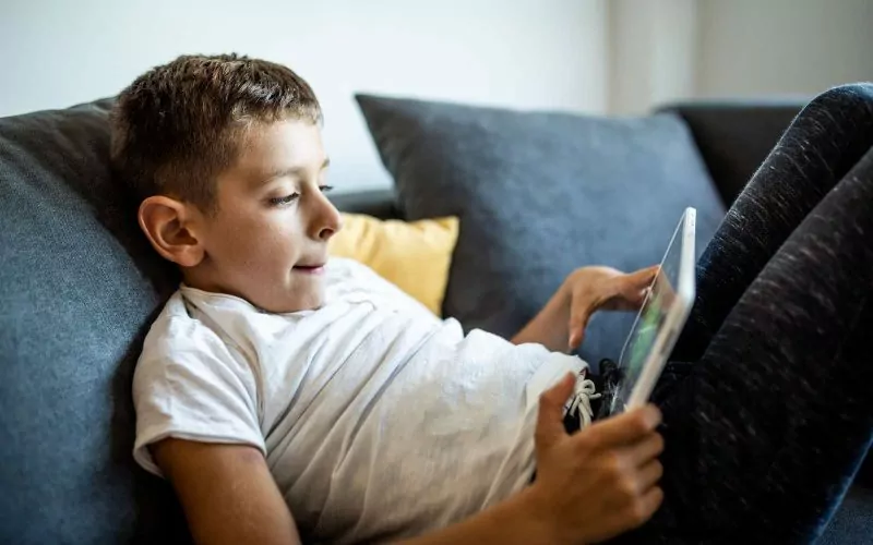 Dreng sidder på sofa med iPad