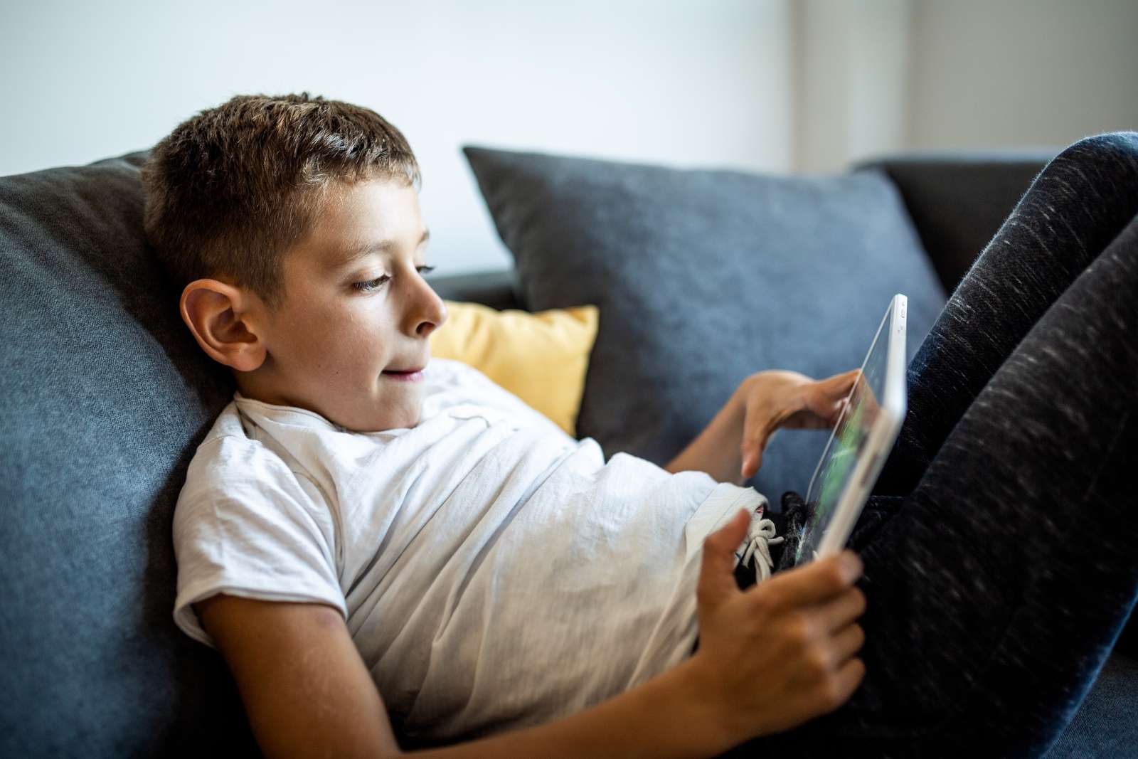 Dreng sidder på sofa med iPad