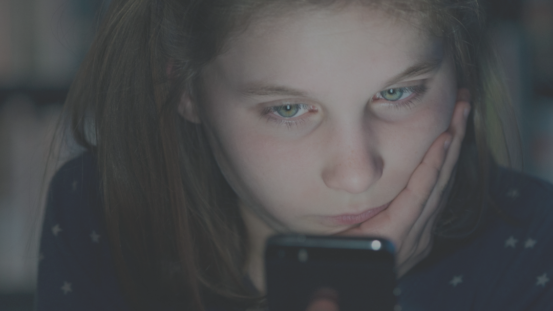 Brunhåret pige med grønne øjne kigger ind på en telefon.