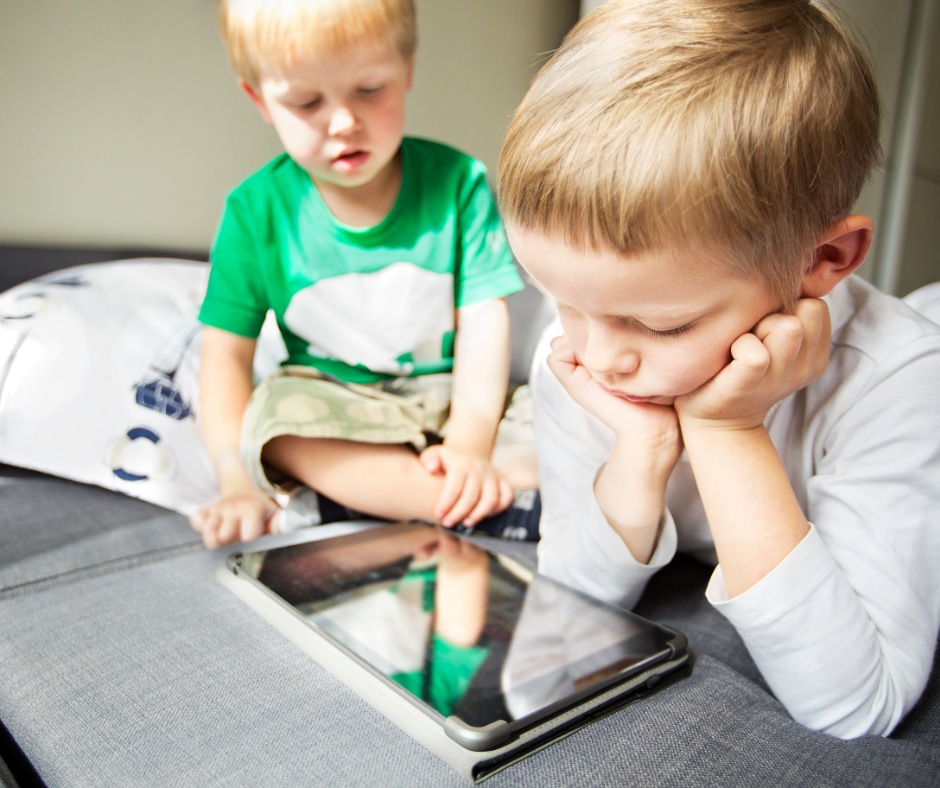 To små, lyshårede drenge kigger ned på en iPad.