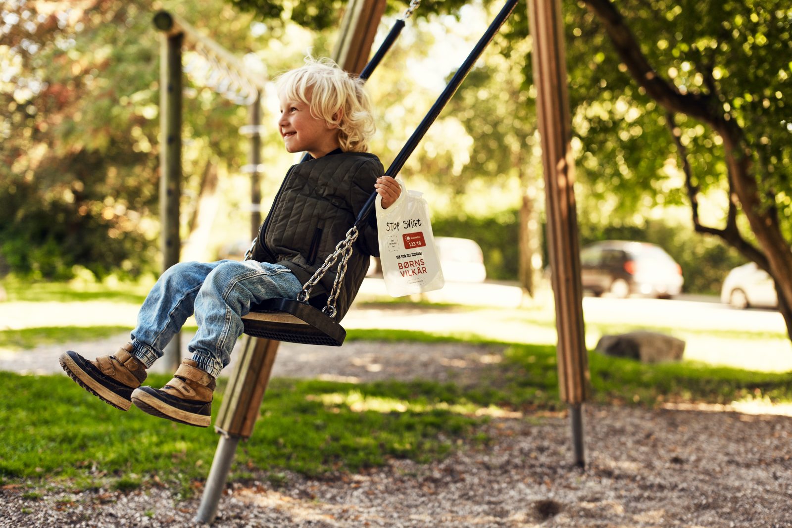 Dreng med indsamlingsbøtte på gynge