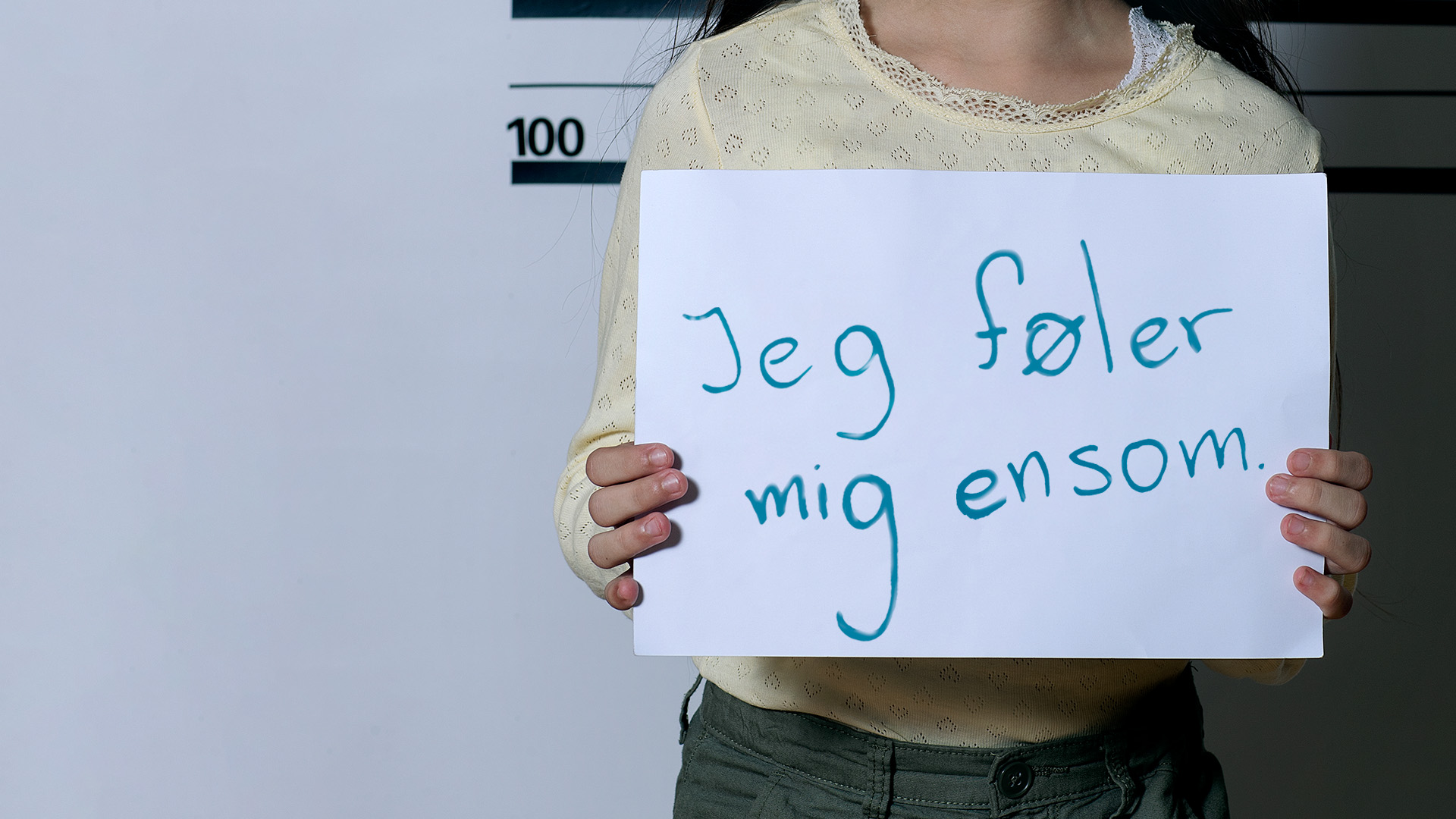 Pige med skilt, hvor der står; 'Jeg føler mig ensom'