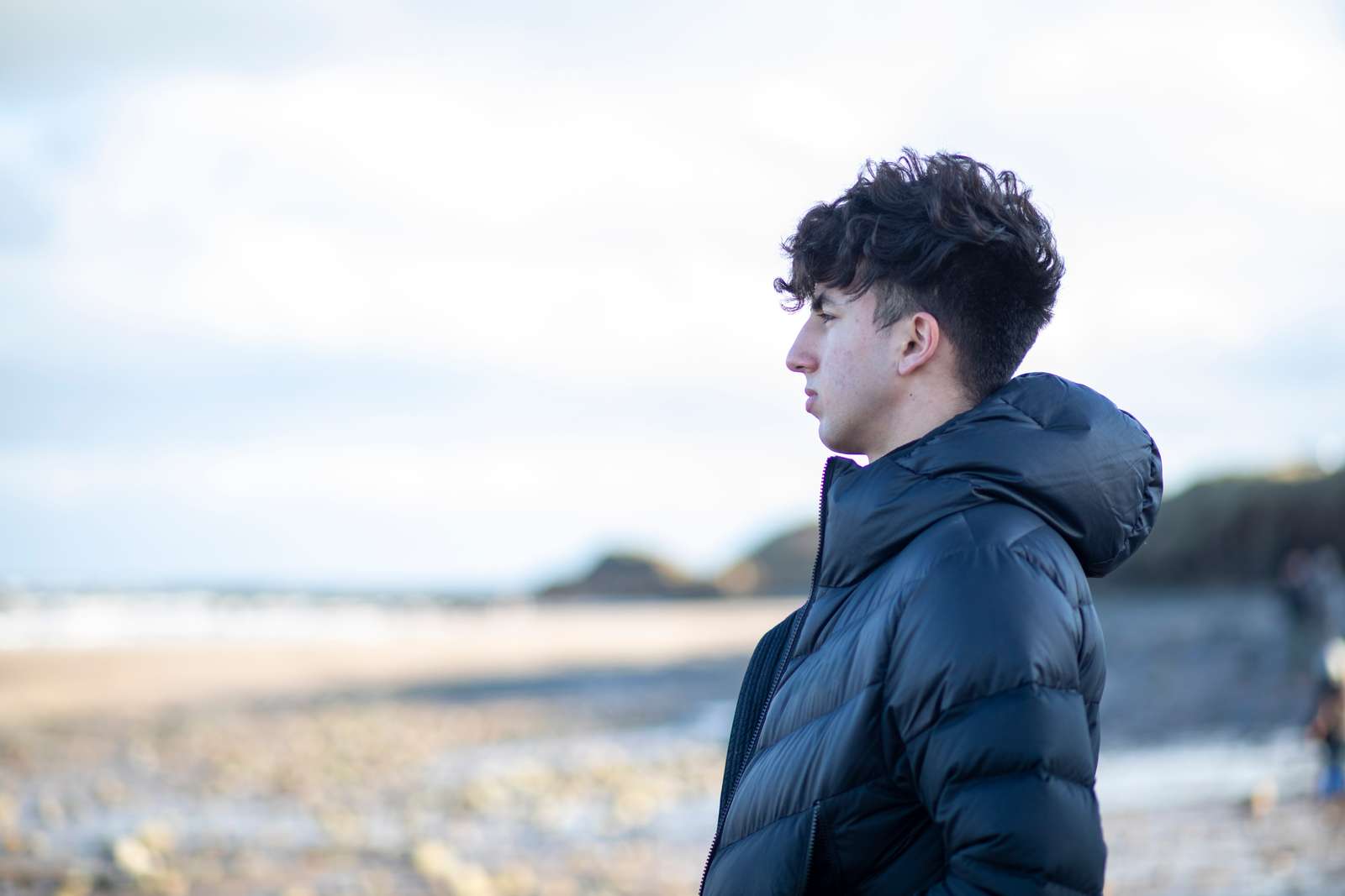 Mørkhåret dreng set i profil kigger ud over kysten