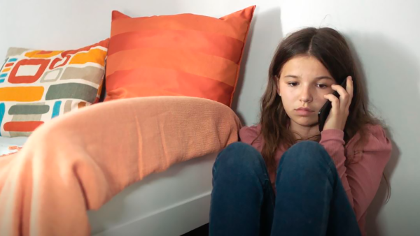 Pige sidder på gulvet og taler i telefon