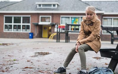 Pige sidder udenfor på bænk