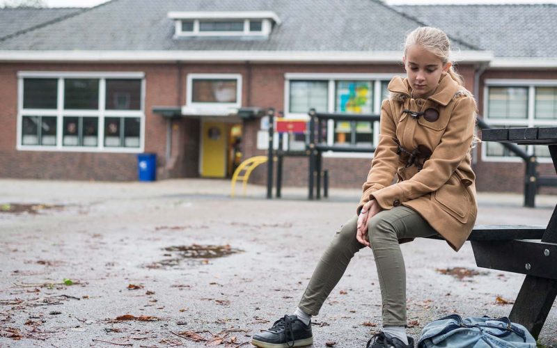 Pige sidder udenfor på bænk