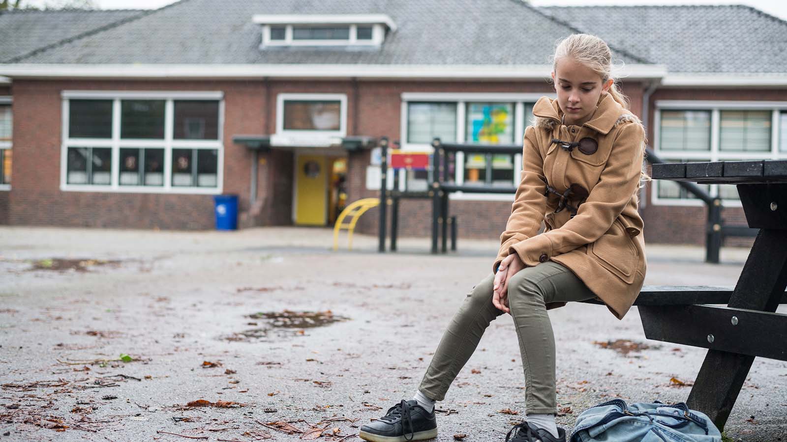 Pige sidder udenfor på bænk