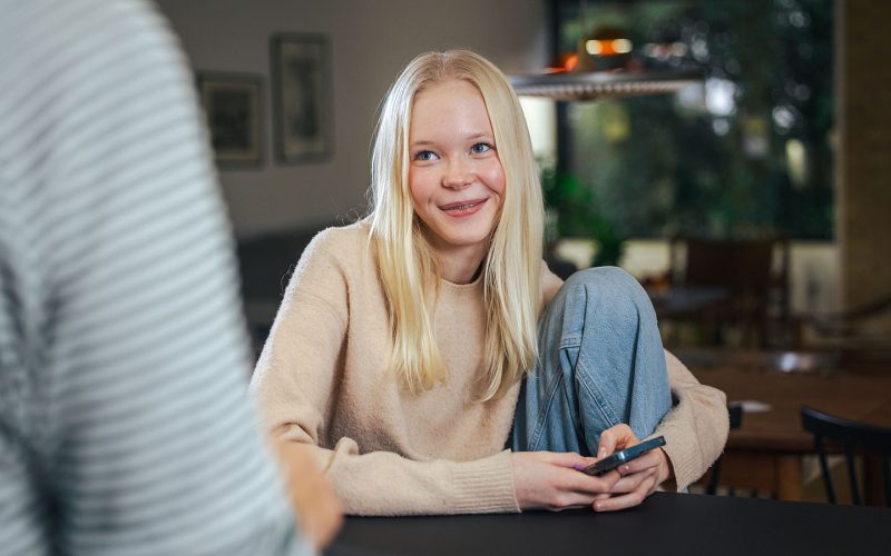 Pige sidder med sin telefon