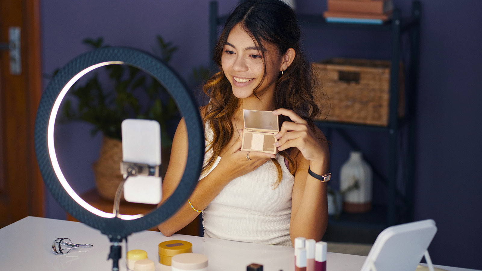 Pige sidder foran sin telefon med sin makeup