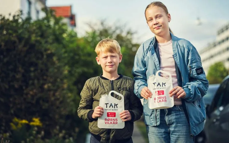 En dreng og en pige står med deres indsamlingsposer fra landsindsamlingen