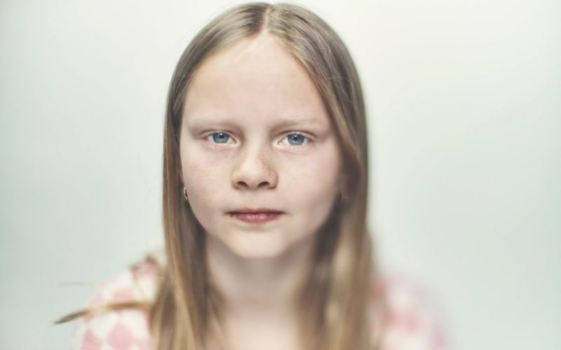 Pige på hvid baggrund kigger ind i kameraet